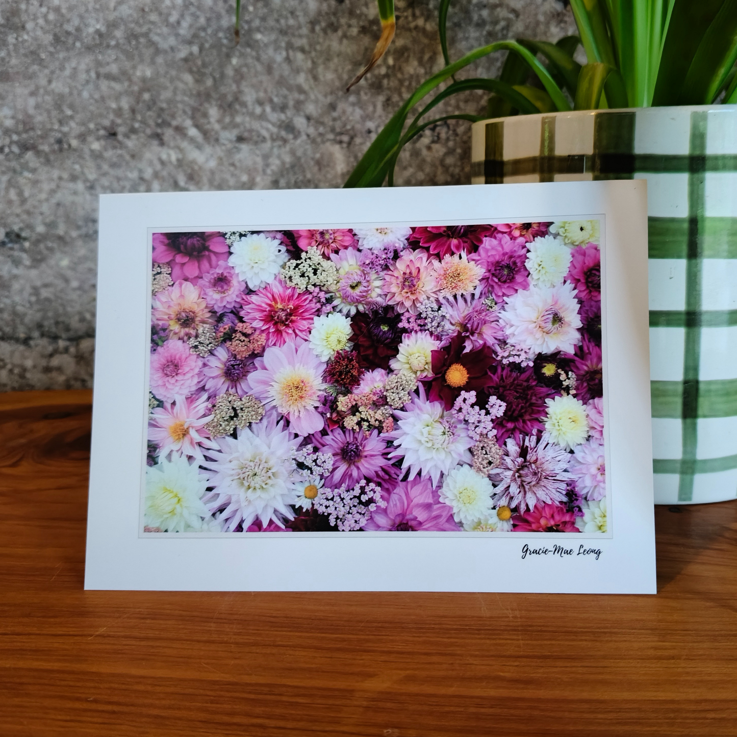 Floral card on a wooden surface with a plant in the background